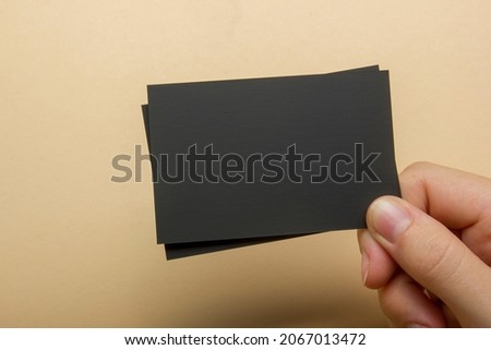 Hand holding white business card on abstract background
