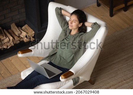 Top view serene woman relaxing in armchair with computer on laps, put hands behind head enjoy carefree leisure, airconditioner climate control inside modern cozy cottage house for comfort life concept Royalty-Free Stock Photo #2067029408