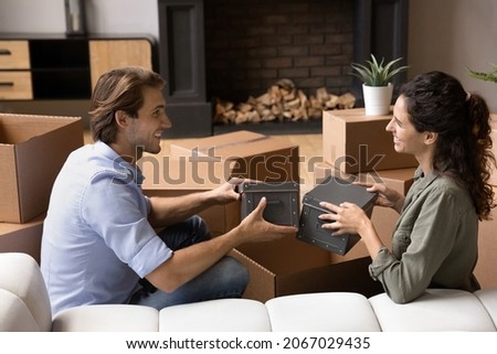 Young couple in love unpack belongings sit on sofa in their new house at relocation day, enjoy life changes, start living together. Cohabitation, bank loan, happy homeowners family, moving concept