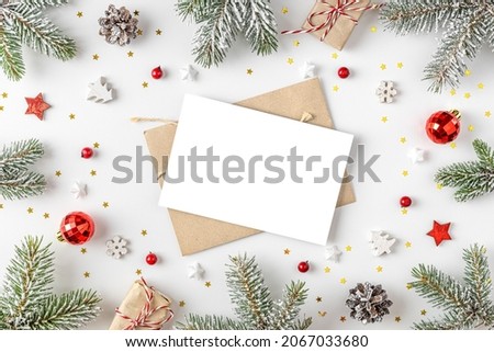 Christmas or Happy New Year greeting card in frame made of fir tree branches, holiday decorations on white background. Flat lay. Mock up. Top view with copy space