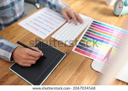 Graphic designer works on computer and selects color schemes