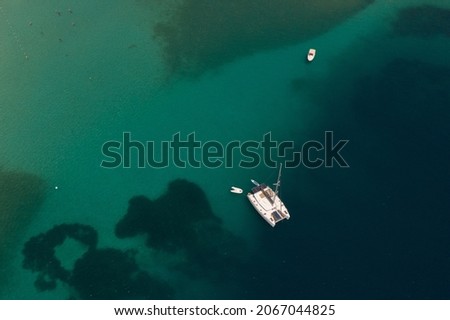 Aerial shot of moored catamaran on turquoise sea on a reef in Greece