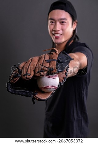 Asian male model with baseball glove isolated on dark background. Baseball player concept