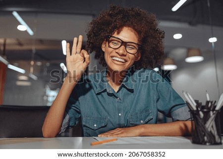 Smiling African American lady in glasses communicating in sign language while looking at camera Royalty-Free Stock Photo #2067058352