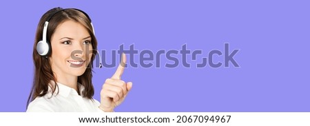 Call center service. Customer support female phone sales operator in white confident cloth, headset showing pointing clicking at copy space, imaginary or slogan text, on violet purple color background