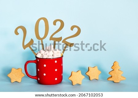 Christmas or New Year 2022 creative concept. Hot chocolate in red mug and golden numbers 2022, copy space