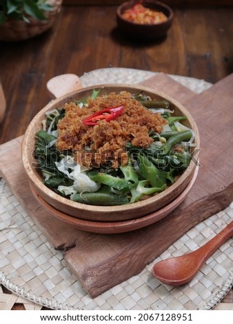 Urap Vegetables in a wooden plate, is an Indonesian salad dish in the form of cooked (boiled) vegetables mixed with seasoned grated young coconut as a flavor enhancer