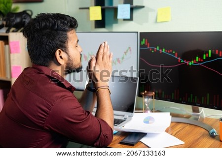 Worried trader praying god to make profit or stock market to go up infront of charts on computer screan - Concept of risk in crypto trading and investing on equity shares Royalty-Free Stock Photo #2067133163
