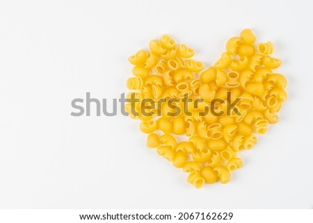 pasta is laid out in the shape of a heart.  Food background and valentine concept. Pasta in shape of heart isolated on white background. durum flour products Royalty-Free Stock Photo #2067162629