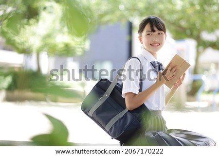 Junior high school student sitting on a park bench and reading Royalty-Free Stock Photo #2067170222