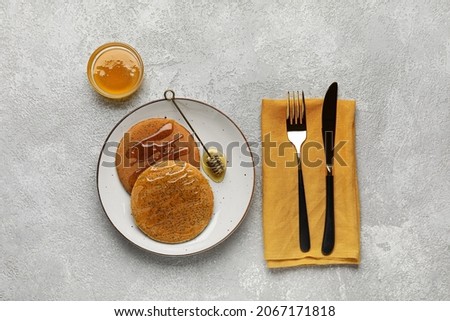 Plate of tasty pancakes with honey on light background