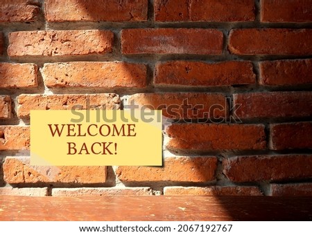 Brown wall brick background with handwritten stick note WELCOME BACK, business re-opening customer or staff greeting after temporary closed on renovation or coronavirus covid-19 pandemic lockdown