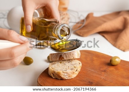 Woman pouring tasty olive oil from bottle, closeup