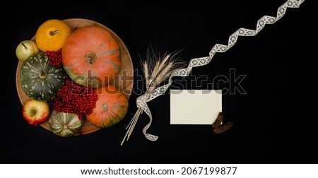Top view of Thanksgiving pumpkin decoration banner with rustic paper holiday greeting card mockup on black background. 