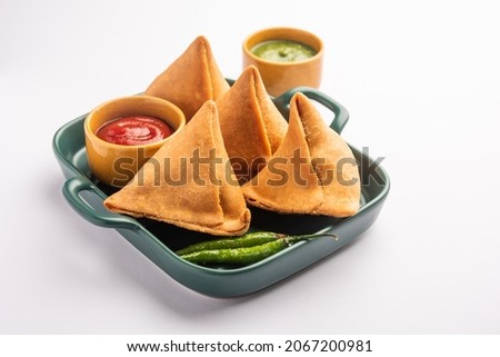 Veg Samosa - is a crispy and spicy Indian triangle shape snack which has crisp outer layer of maida  filling of mashed potato, peas and spices Royalty-Free Stock Photo #2067200981