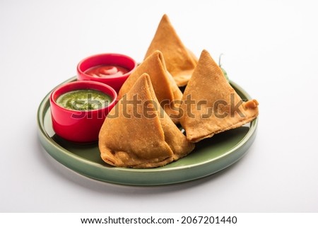 Veg Samosa - is a crispy and spicy Indian triangle shape snack which has crisp outer layer of maida  filling of mashed potato, peas and spices Royalty-Free Stock Photo #2067201440