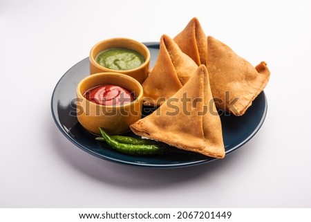 Veg Samosa - is a crispy and spicy Indian triangle shape snack which has crisp outer layer of maida  filling of mashed potato, peas and spices Royalty-Free Stock Photo #2067201449