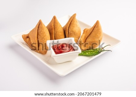 Veg Samosa - is a crispy and spicy Indian triangle shape snack which has crisp outer layer of maida  filling of mashed potato, peas and spices Royalty-Free Stock Photo #2067201479