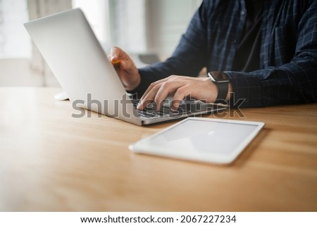 The laptop is open on the table. Online accounting of expenses in business. Workplace in the new office. A man works with papers and counts finances.