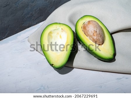 Avocado cut in half on a gray background and fabric.