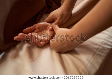Massage therapist stimulating reflex point on client hand