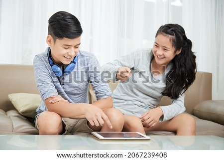 Teenage brother and sister fighting when deciding what to watch on tablet computer Royalty-Free Stock Photo #2067239408