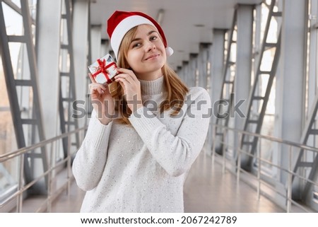 attractive woman in a sweater with a Santa hat with a gift for the New Year