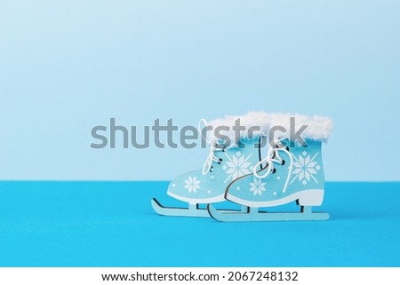 Beautiful blue ice skating toys on a two-tone blue background. Winter sports and entertainment.