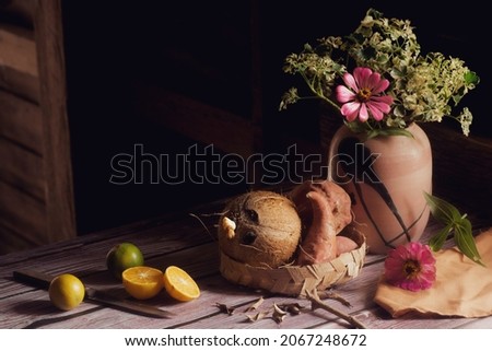 A picture of a vase of flowers with small orange fruit placed nearby.