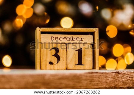 Wooden calendar of blocks with the date of December 31 on the Christmas and New Year blurred background. Beautiful warm light bokeh. New Year mood. Photo