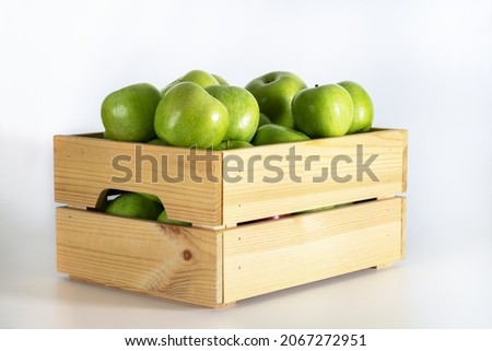 Wooden box of green apples on a white background.