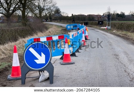 Roadworks with traffic cones and warning sign on a rural country road in Buckinghamshire, UK