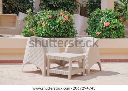 Plastic wicker garden furniture set. A table and two armchairs made of wicker plastic. Lightweight portable garden furniture for a country house, terraces. Royalty-Free Stock Photo #2067294743