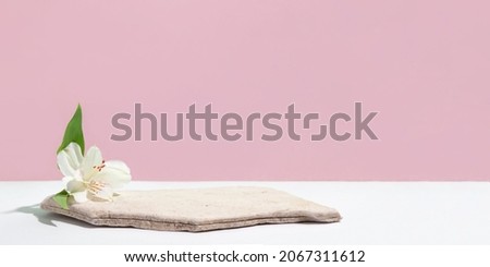 Background for cosmetic products of natural pink color. Stone podium with white flowers. Front view.