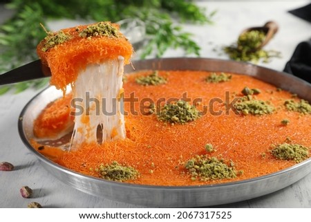 Arabic traditional kunafa. desserts rough konafa in tray sweet with pistachio and pine on top. close up Royalty-Free Stock Photo #2067317525