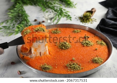 Arabic traditional kunafa. desserts rough konafa in tray sweet with pistachio and pine on top. top view Royalty-Free Stock Photo #2067317531