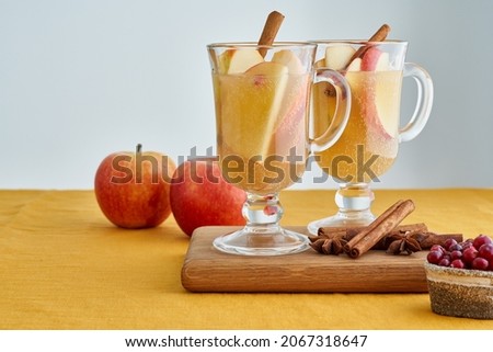 Apple cider. Two glasses of hot white mulled wine beverages with cardamom, cinnamon on wooden board on linen tablecloth. Apple toddy. Seasonal winter beverage. Selective focus, blurred background Royalty-Free Stock Photo #2067318647