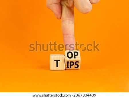 Top tips symbol. Businessman turns a wooden cube with words 'Top tips'. Beautiful orange table, orange background. Top tips and business concept. Copy space.