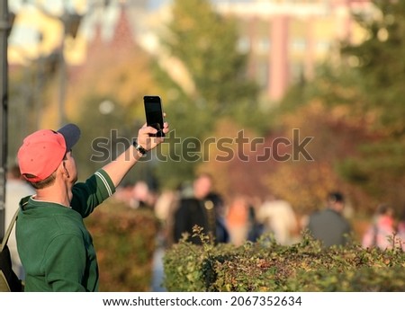 Young man takes a selfie with a smartphone on the autumn embankment