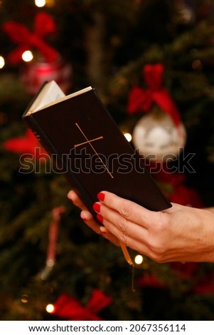 Woman reading the bible with Christmas tree in background.  Geneva. Switzerland. 12202020