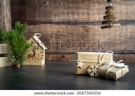 Christmas and zero waste, ecological packaging. Gifts wrapped in craft paper with snowflakes and wooden star on a wooden background. Ecological Christmas party concept, ecological decor with wood.