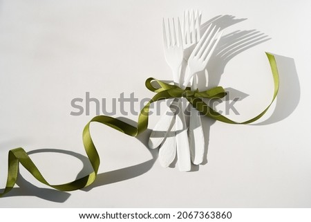 white forks of different shapes lie on a white background, tied on a bow with a beautiful decorative green ribbon