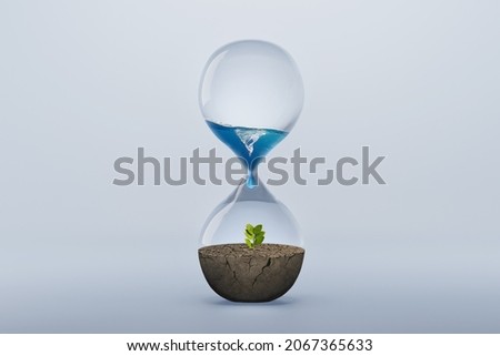 Hourglass with fresh water drop to green plant planting on dry land isolated background, metaphoric of saving water, Drought and Climate change. Royalty-Free Stock Photo #2067365633