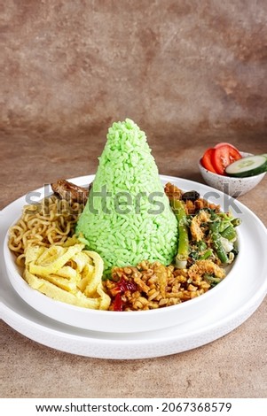 Nasi Tumpeng Pandan is dome shape pandan green rice with various side dish. Royalty-Free Stock Photo #2067368579