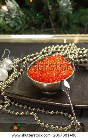 Red caviar in a ceramic bowl, silver beads and pearls on a silver tray. Christmas and New Year background
