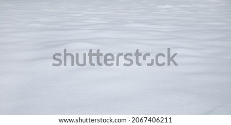 Natural winter background with snow drifts. Snowy clean field. Nature Winter texture for Design of fresh fuffy snow. Wintertime. Beautiful snowdrifts