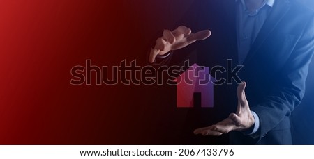 Businessman male hand holding house icon on blue background. Property insurance and security concept.Real estate concept.Banner with copy space