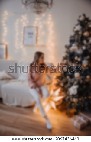 Blurred pretty attractive woman sitting near Christmas tree.happy young woman celebrating Christmas.New year decorations. celebrating the New Year at home.Christmas tree at home.