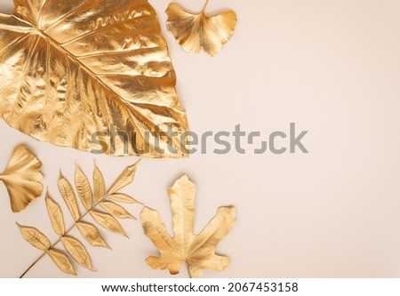 Gold tropical mix leaves on beige background. Flat lay, top view minimal concept