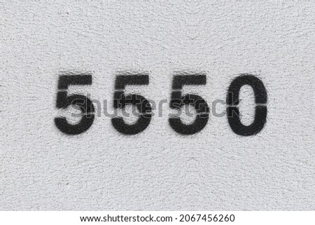 Black Number 5550 on the white wall. Spray paint. Number five thousand five hundred fifty.